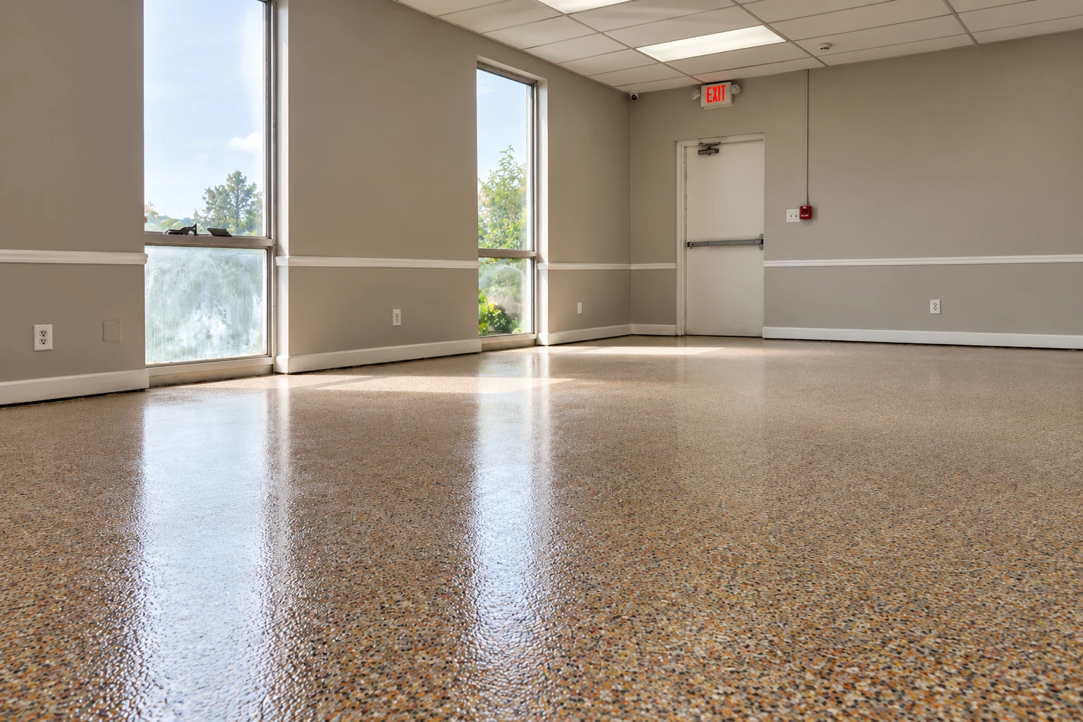 Glossy, multicolored epoxy floor in an empty commercial room with tall windows and an exit door.