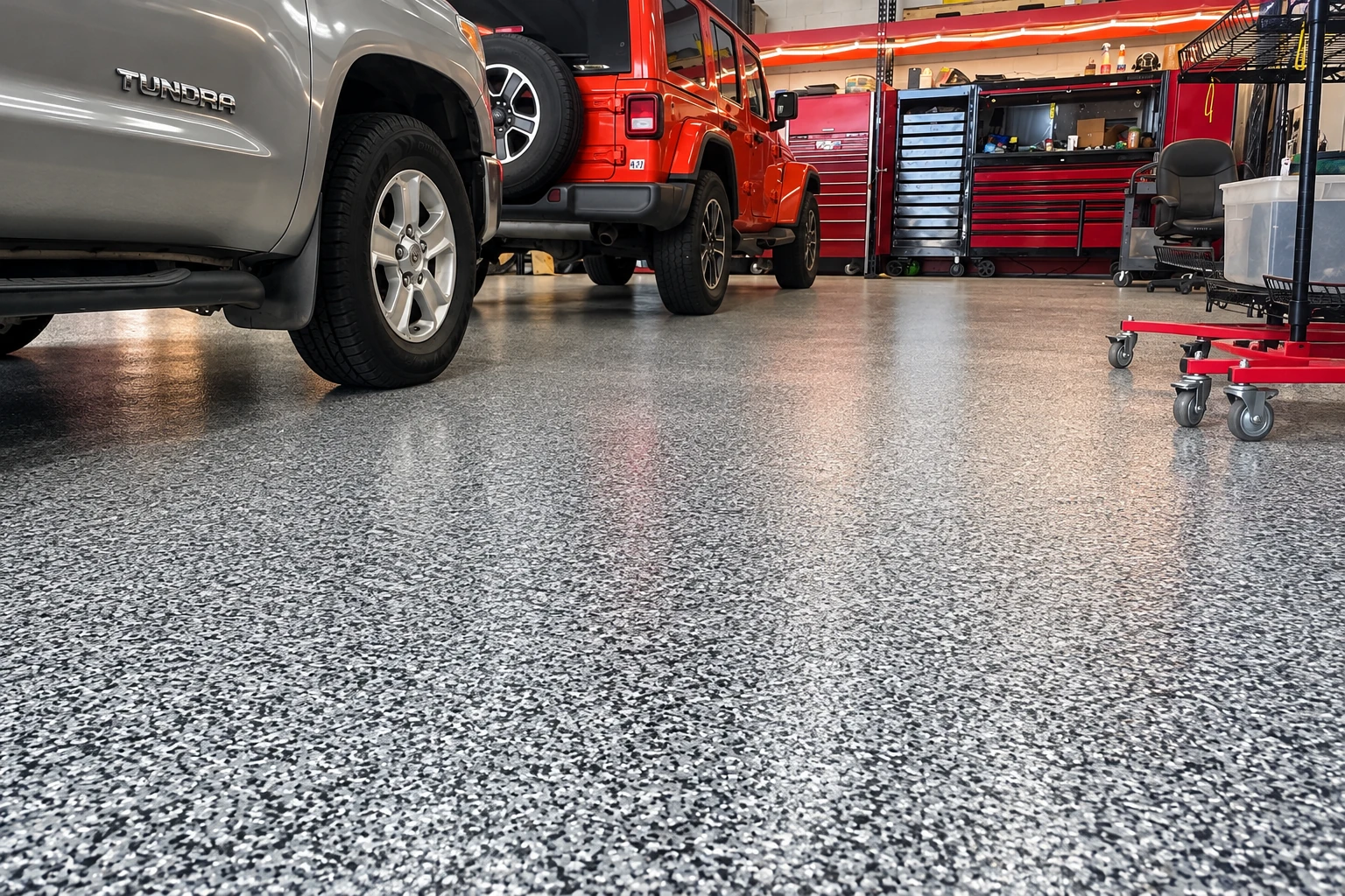 A workshop garage with two vehicles, tool cabinets, and a reflective gray flake-coated floor.