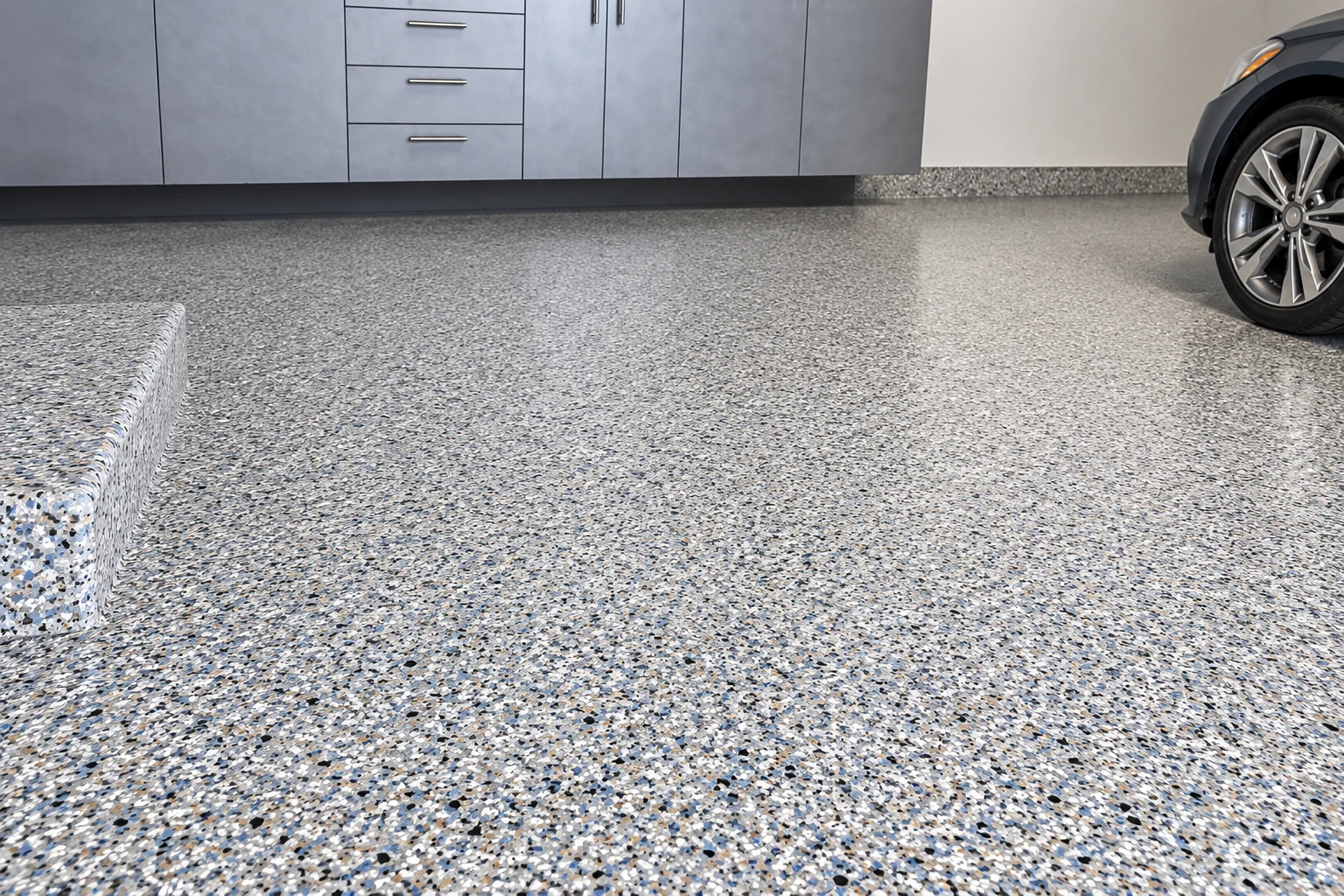 A gray flake-coated garage floor extends beneath storage cabinets beside a partially visible car.