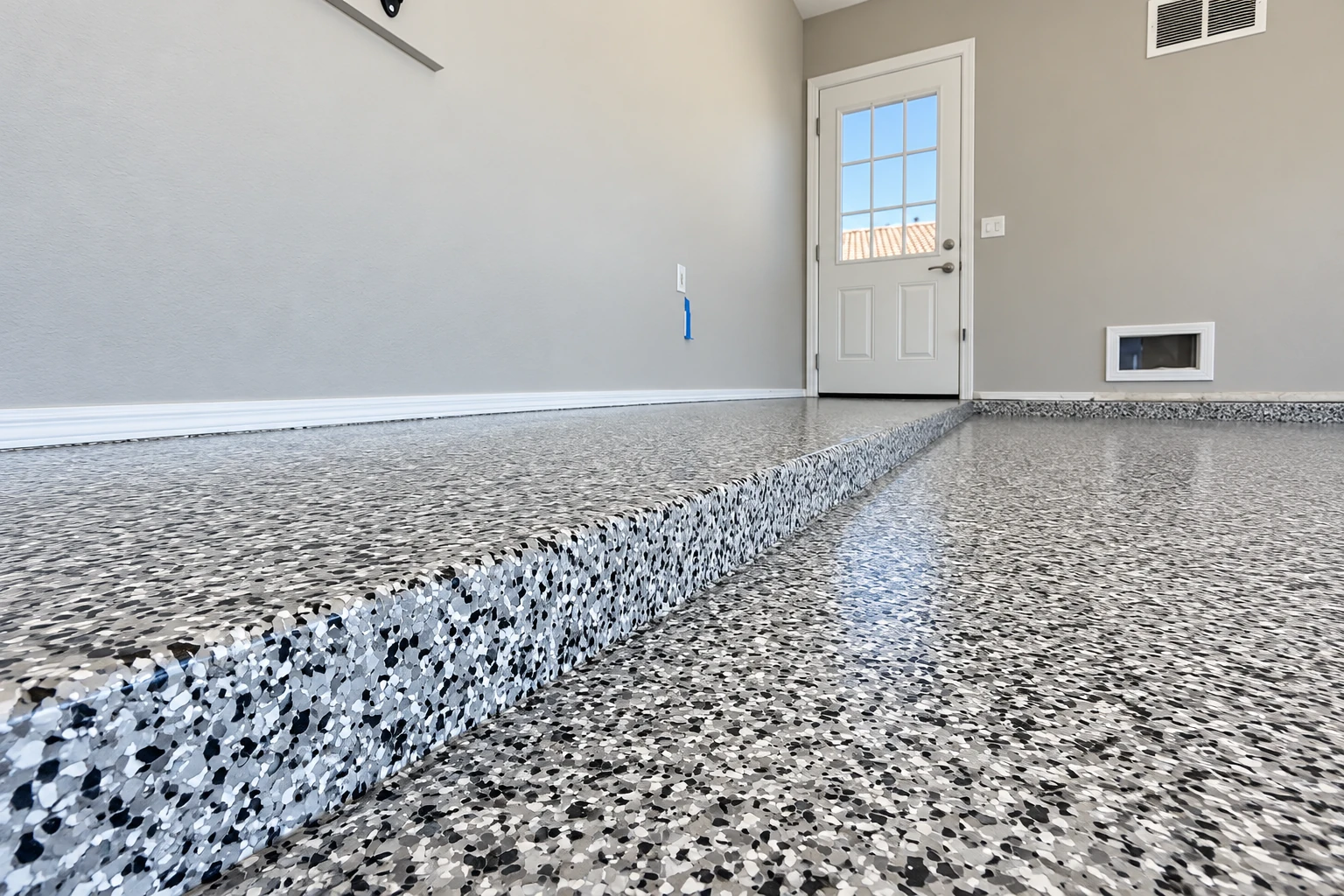 A glossy black, white, and gray flake floor coats a raised garage platform and lower level.